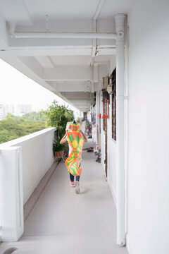 Girl wearing lion head running along HDB corridor
