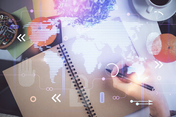 Multi exposure of hands making notes with world map hologram and data theme icons. Concept of global computer data.