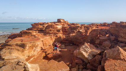 Couple hiking the red and rocky coastline of Broome in Austrlia