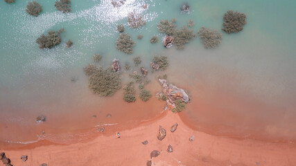 Drone view of red sand beach and turquoise water