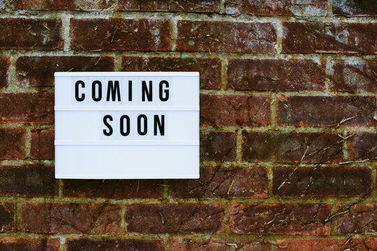 The words coming soon spelled out on a cinematic light-box on a brick wall