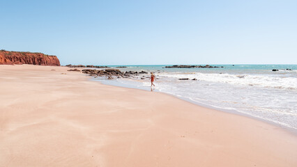 Woman running at the red sand beach