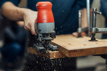 male carpenter working with electric jigsaw and wood