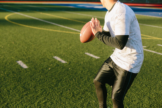 Athletic Man Preparing To Throw Football On Artificial Turf Field