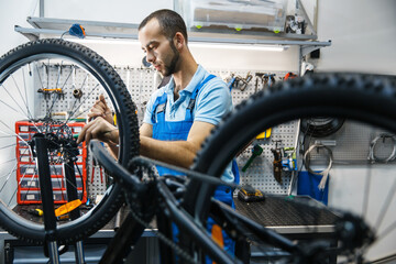 Bicycle repair in workshop, man setting up brake