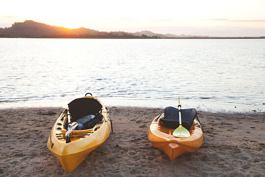 Yellow kayaks sit on a beach at sunset after a day paddling