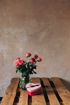 Bouquet of roses and a Valentine's gift on the table