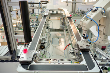 Industry 4.0 concept; artificial intelligence in smart factory prototype. The robot picks up the product from an automated car on the production line. Focus on the robotic arm's gripper.