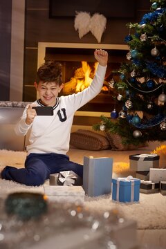 Cute schoolboy playing happy with mobilephone at christmas time.