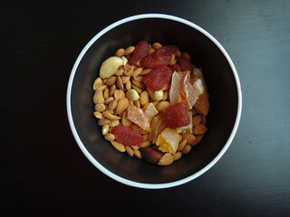 candied almonds and cashews in a black plate on a dark background.
