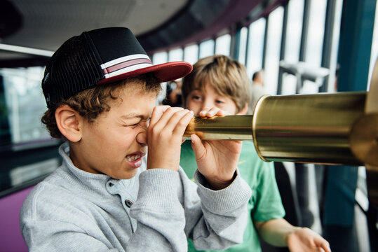 Side view of boy looking through gold telescope