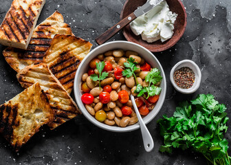 Ingredients for  goats cheese crostini with garlicky beans on a dark background, top view