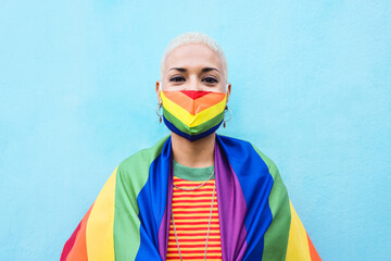Young lesbian woman wearing rainbow mask and flag - Lgbt and gay pride concept