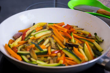Close-up of white pan with a mix of sliced vegetables, carrots, zucchini, eggplant and peppers - healthy eating vegetarian vegan concept