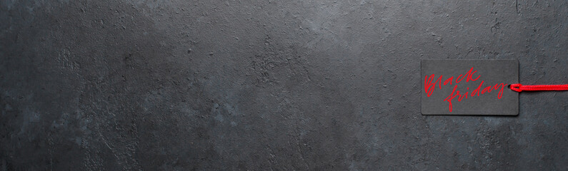 Black Friday - red handwritten inscription on a dark concrete background. The black tag. Copy...
