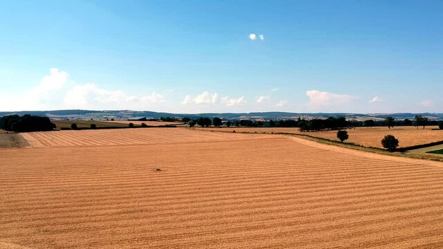 Slow forwards moving drone shot of wheat fields, near small village Taize in France.