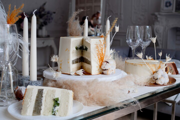 Beautiful wedding cake with cream and kiwi, table setting and a piece of cake on a plate.