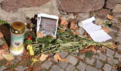 Kerze, Blumen und Zettel an der Mauer vor der Synagoge in Halle (Saale)