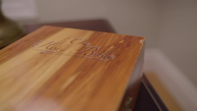 Wrap around wooden book box labeled Holy Bible on side table