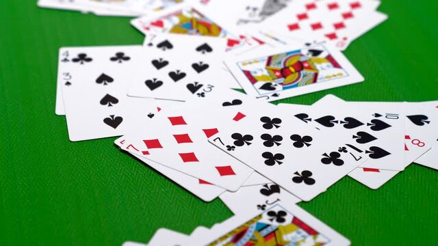 A pile of poker cards facing up being pushed into frame on a poker table in 4K