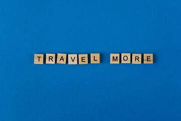 The words travel moor is lined with wooden letters on a blue background top view. Postcard in place for text. Flatlay. The words. Banner.
