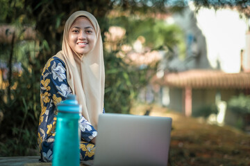 Photo of islamic female student  wearing headscarf with laptop