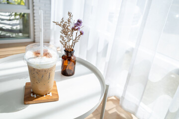 Iced coffee on table in cafe with sunlight through the curtains.