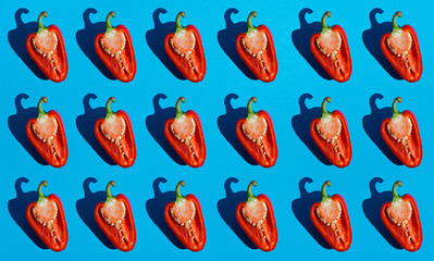 Red sliced bell pepper seamless pattern with dark black deep shadows on blue background flat lay. Minimalistic abstract image. Healthy organic concept. Top view, copy space