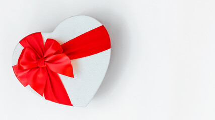 banner of gift in white box in shape of  heart with a red ribbon bow isolated on white background. top view composition for Valentine day, birthday, mother day or christmas. copyspace. isolated.