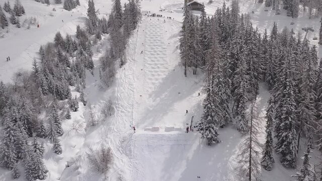 Aerial drone shot over two skiers skiing and racing down the white snowy slopes of Verbier, Switzerland.