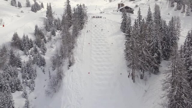 Aerial drone shot over skiers riding down the white snowy slopes in Verbier, Switzerland.