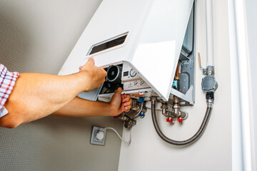 Plumber attaches Trying To Fix the Problem with the Residential Heating Equipment. Repair of a gas...