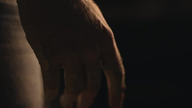 A man shaping clay with his hands on a mill in slow motion.