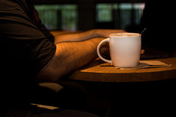 Laptop on a wooden table in a coffee shop with a cup of coffee