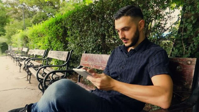 Young Arabian European searching in tinder on a Tablet in the Park