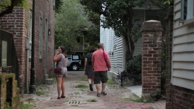 A family walks down a brick alley in Charleston.