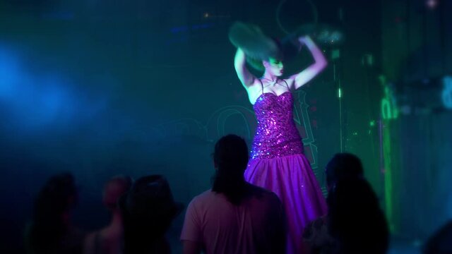 Sexy cabaret burlesque dancer in a sparkling ball gown and fur stole on stage at a live performance