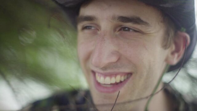 young man in explorer outfits smiles into the distance. In tropical Forest Jungle setting.