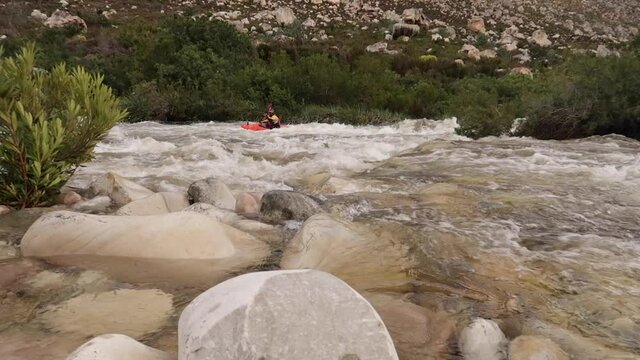 Aerial footage of white water kayaks paddling in the white water rapids on a freestone stream in the western cape of south africa during a winter storm.