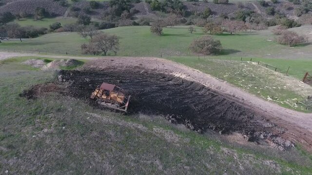 Bulldozer pushing dirt onto hill to rebuild its elegance