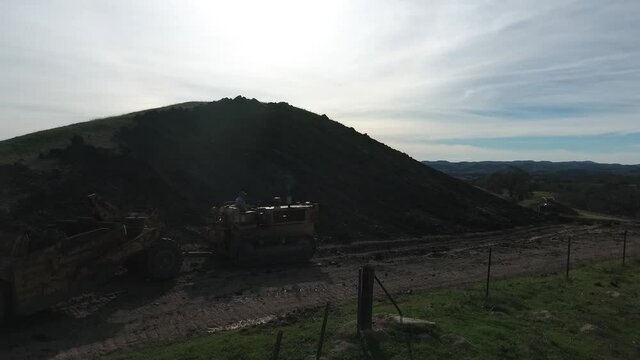 towed scraper hauling mud behind a D5 bulldozer in the green hills