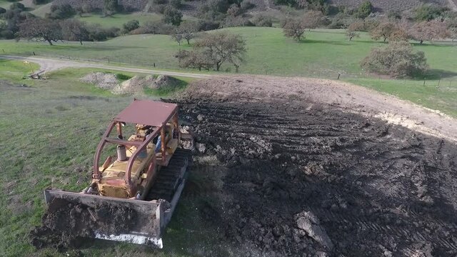 Bulldozer pushing dirt onto hill to rebuild its elegance