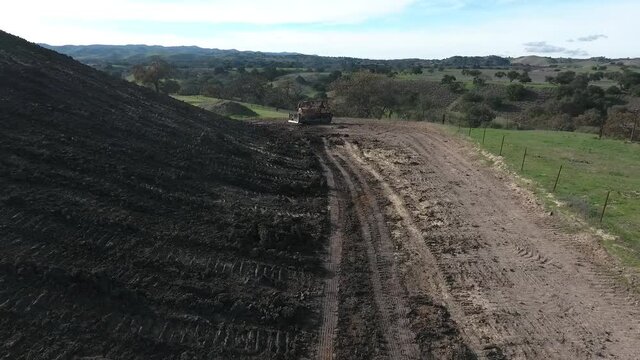 Bulldozer pushing dirt onto hill to rebuild its elegance