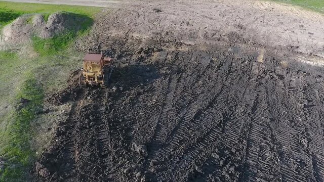 Bulldozer pushing dirt onto hill to rebuild its elegance