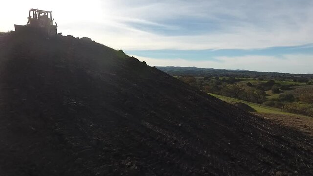 Bulldozer pushing dirt onto hill to rebuild its elegance
