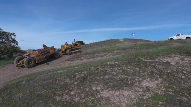 towed scraper hauling mud behind a D5 bulldozer in the green hills