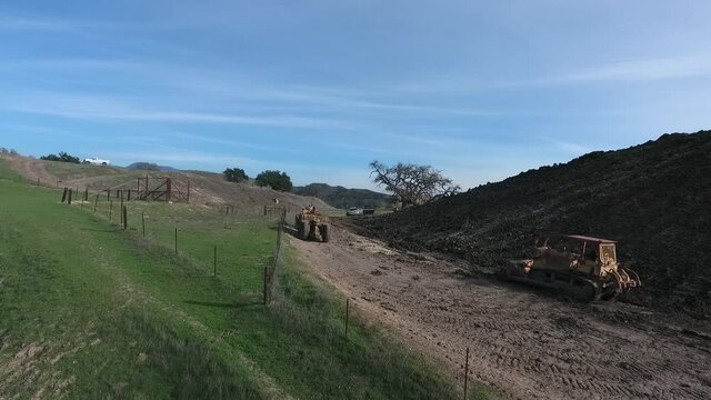 towed scraper hauling mud behind a D5 bulldozer in the green hills
