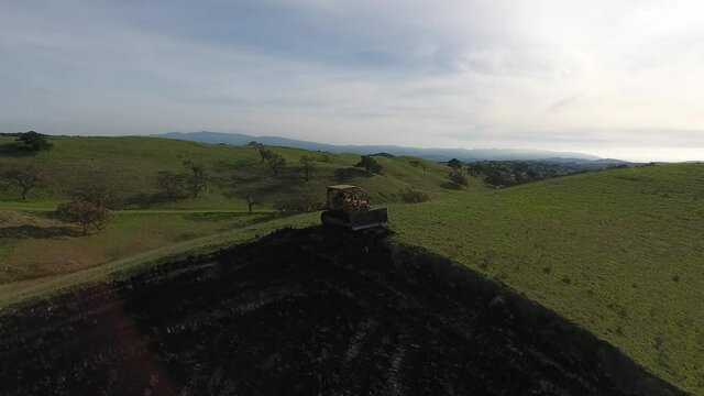 Bulldozer pushing dirt onto hill to rebuild its elegance