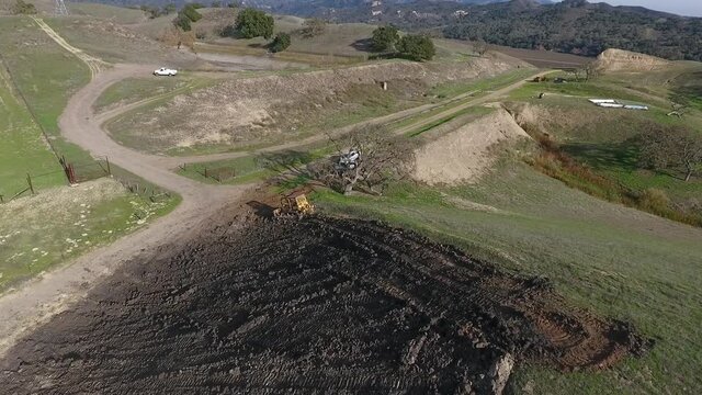 Bulldozer pushing dirt onto hill to rebuild its elegance