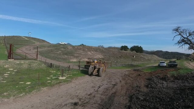 towed scraper hauling mud behind a D5 bulldozer in the green hills